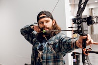 a man with a beard is holding a bow and arrow