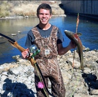 a young man with a bow and arrow holding a fish